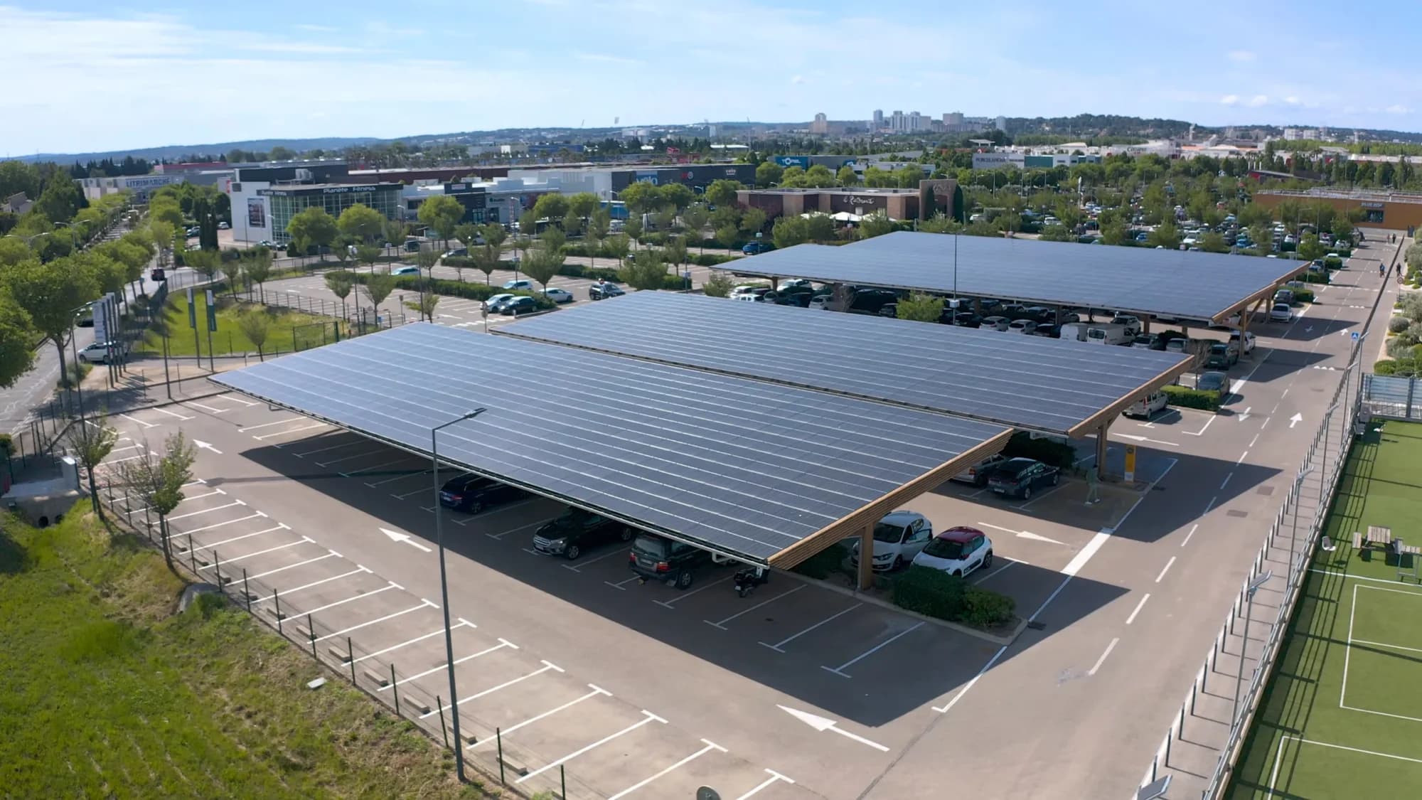 Vue aérienne d'un parking de centre commercial couvert d'ombrières photovoltaïques.